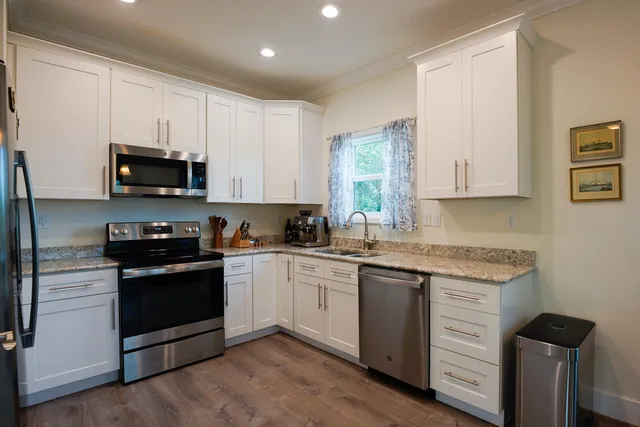 a kitchen with granite countertop white cabinets and black appliances