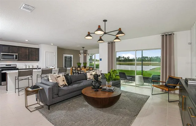 a living room with furniture and a large window with kitchen view