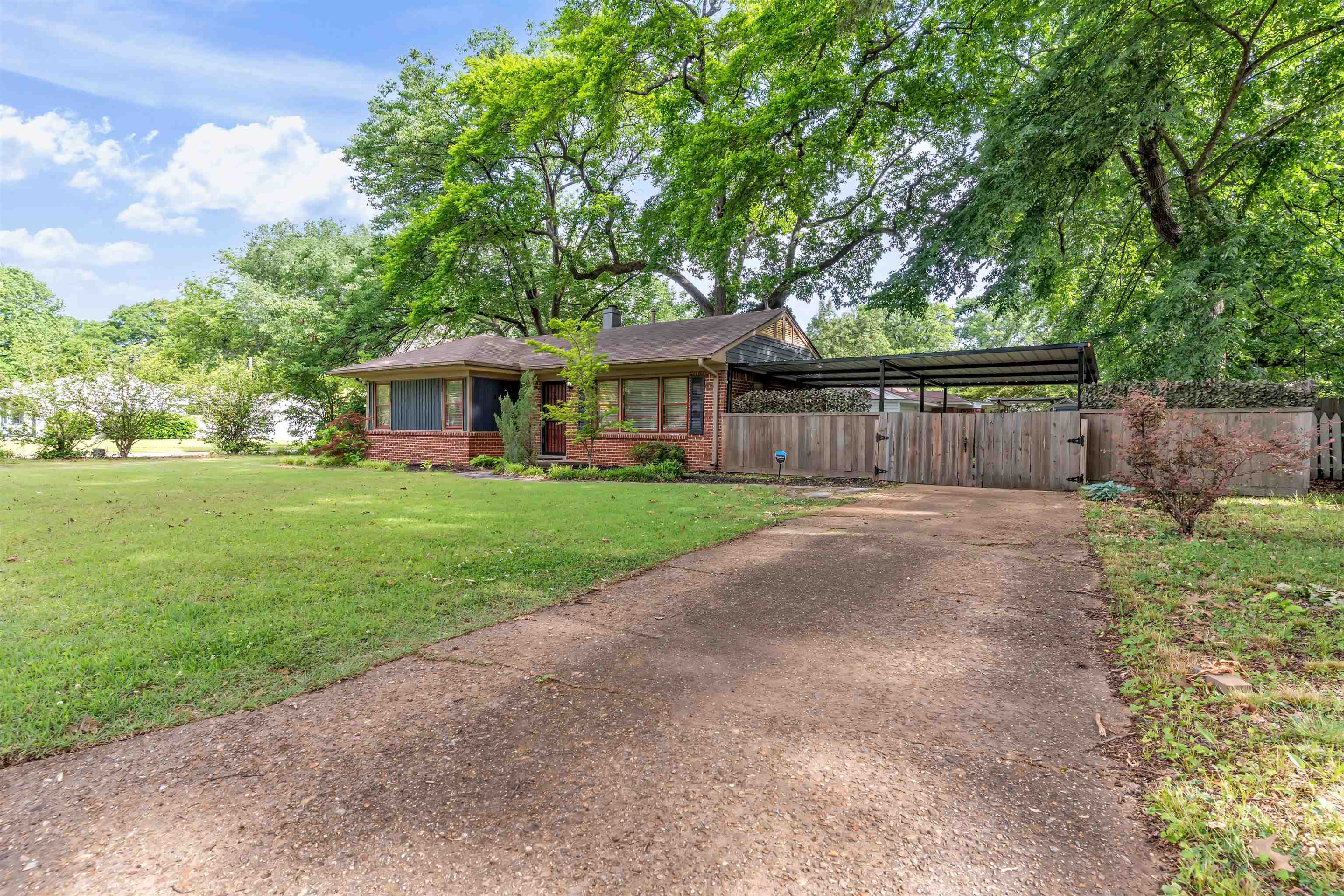 Brick residence with a screened porch, mature tree canopy, and a concrete driveway