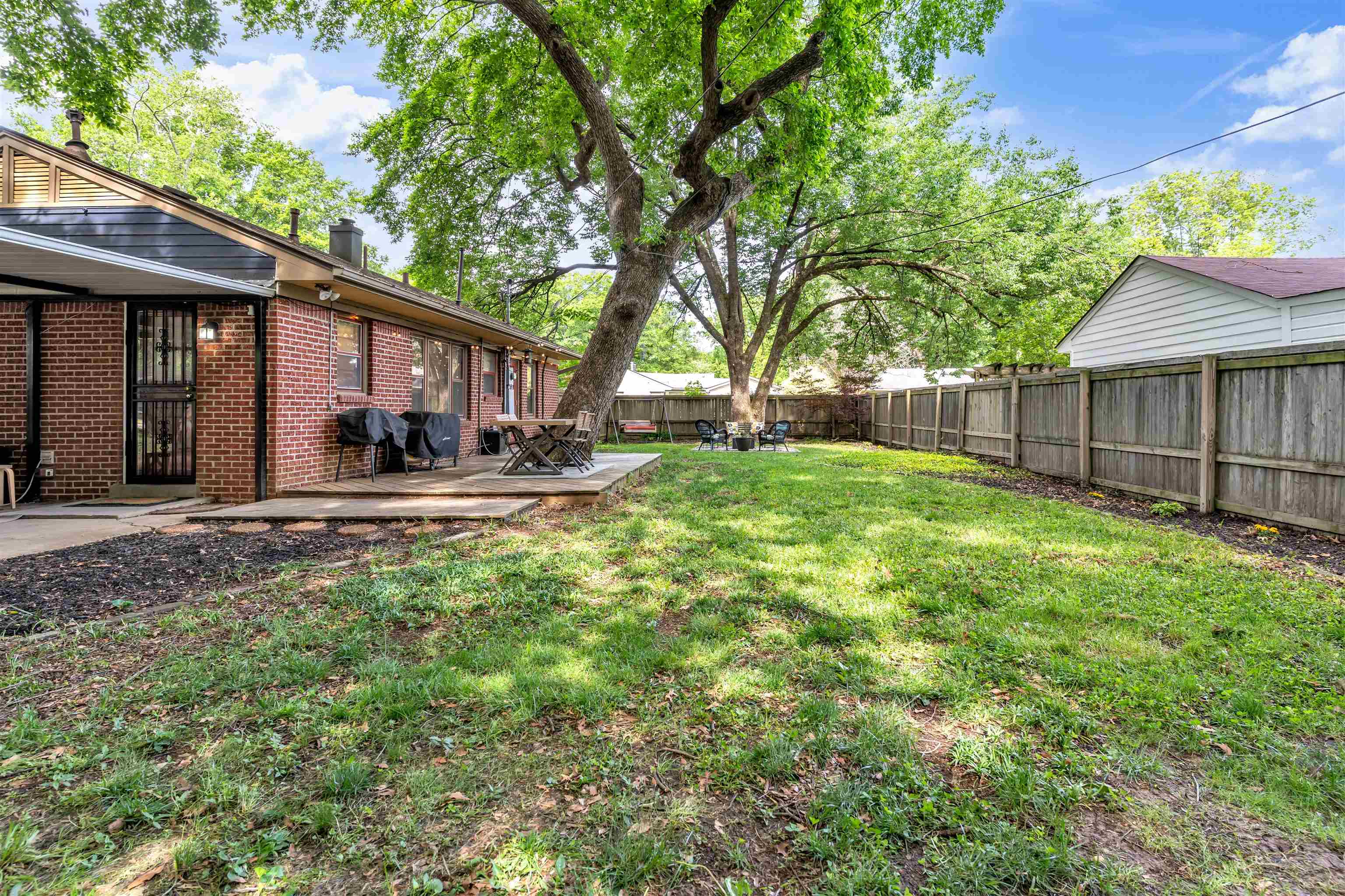 4564 Verne Road Memphis, TN 38117 - Photo 18 of 25 Expansive lawn area featuring a mature tree, wood fencing, and a concrete patio