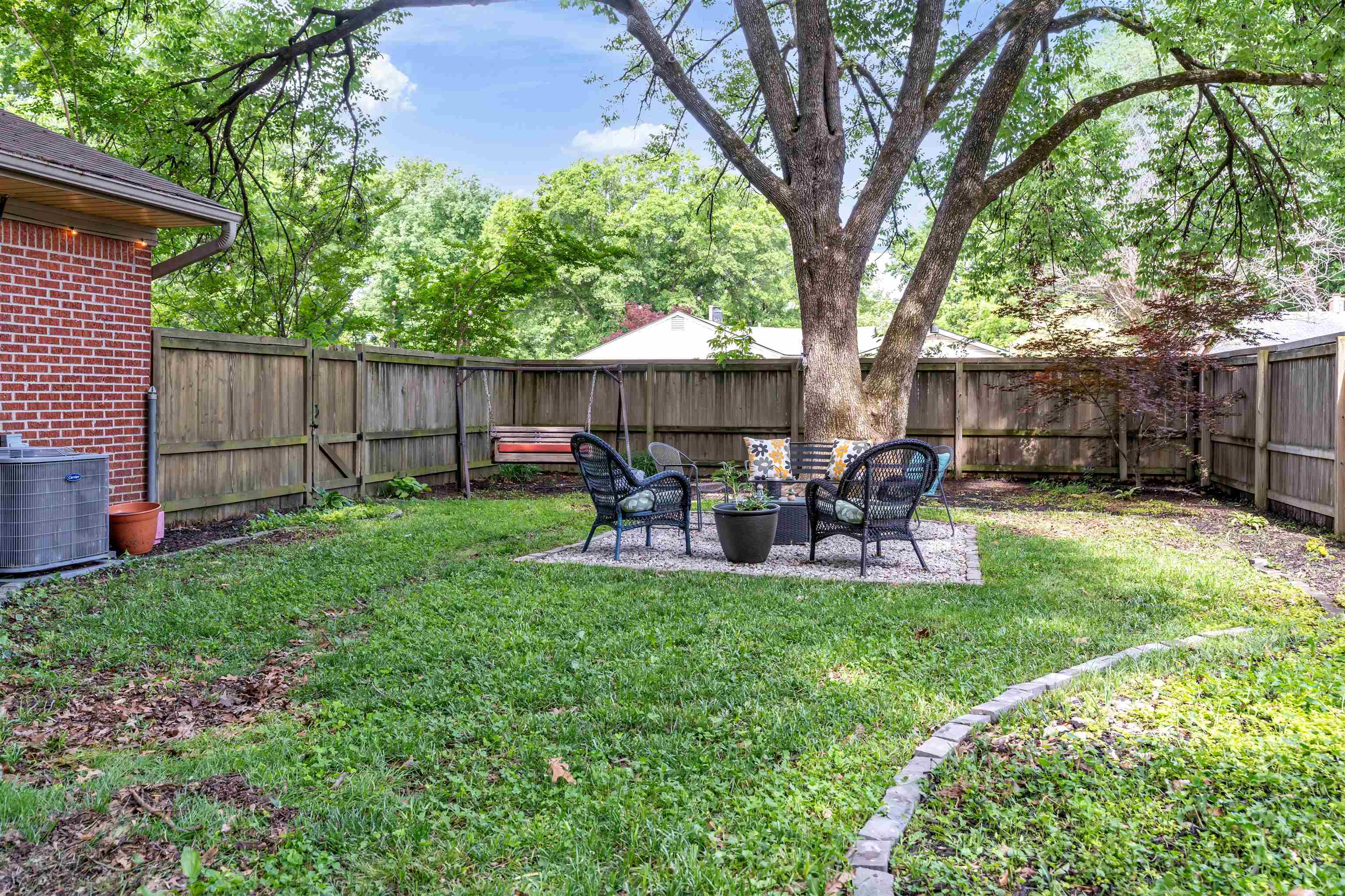 4564 Verne Road Memphis, TN 38117 - Photo 20 of 25 Expansive backyard featuring a large tree, full privacy fencing, brick exterior, and a gravel patio area
