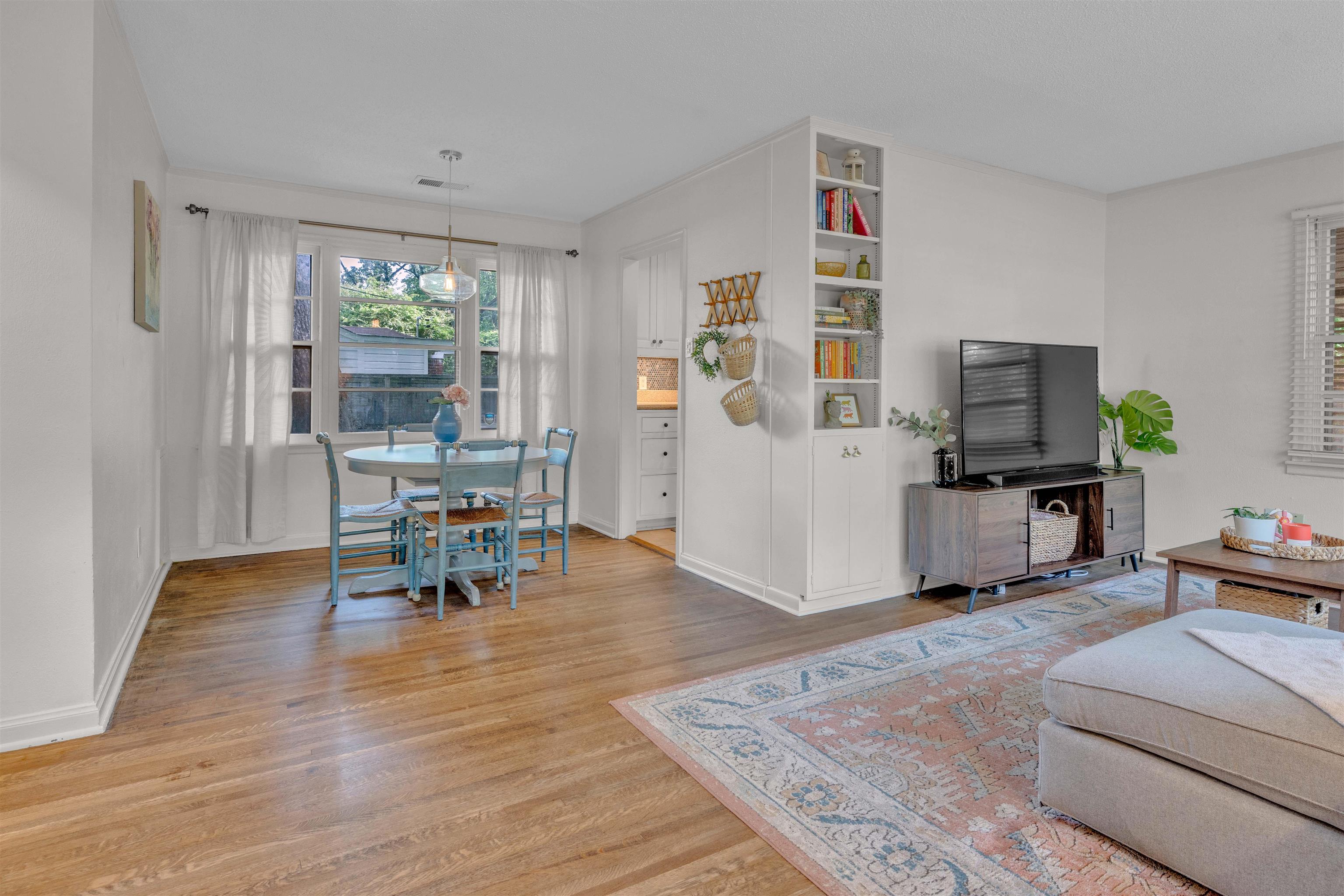 4564 Verne Road Memphis, TN 38117 - Photo 5 of 25 Open-concept living area featuring wood-finish flooring, a dining space with a window, and a built-in shelving unit