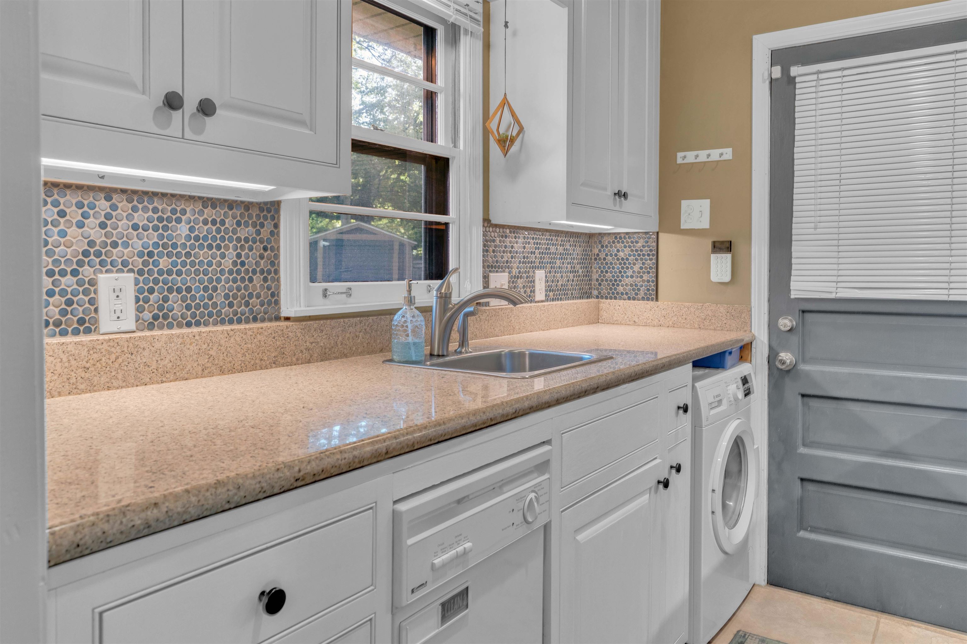 4564 Verne Road Memphis, TN 38117 - Photo 8 of 25 Kitchen area featuring light cabinetry, a stainless steel sink, a dishwasher, and a washer-dryer unit