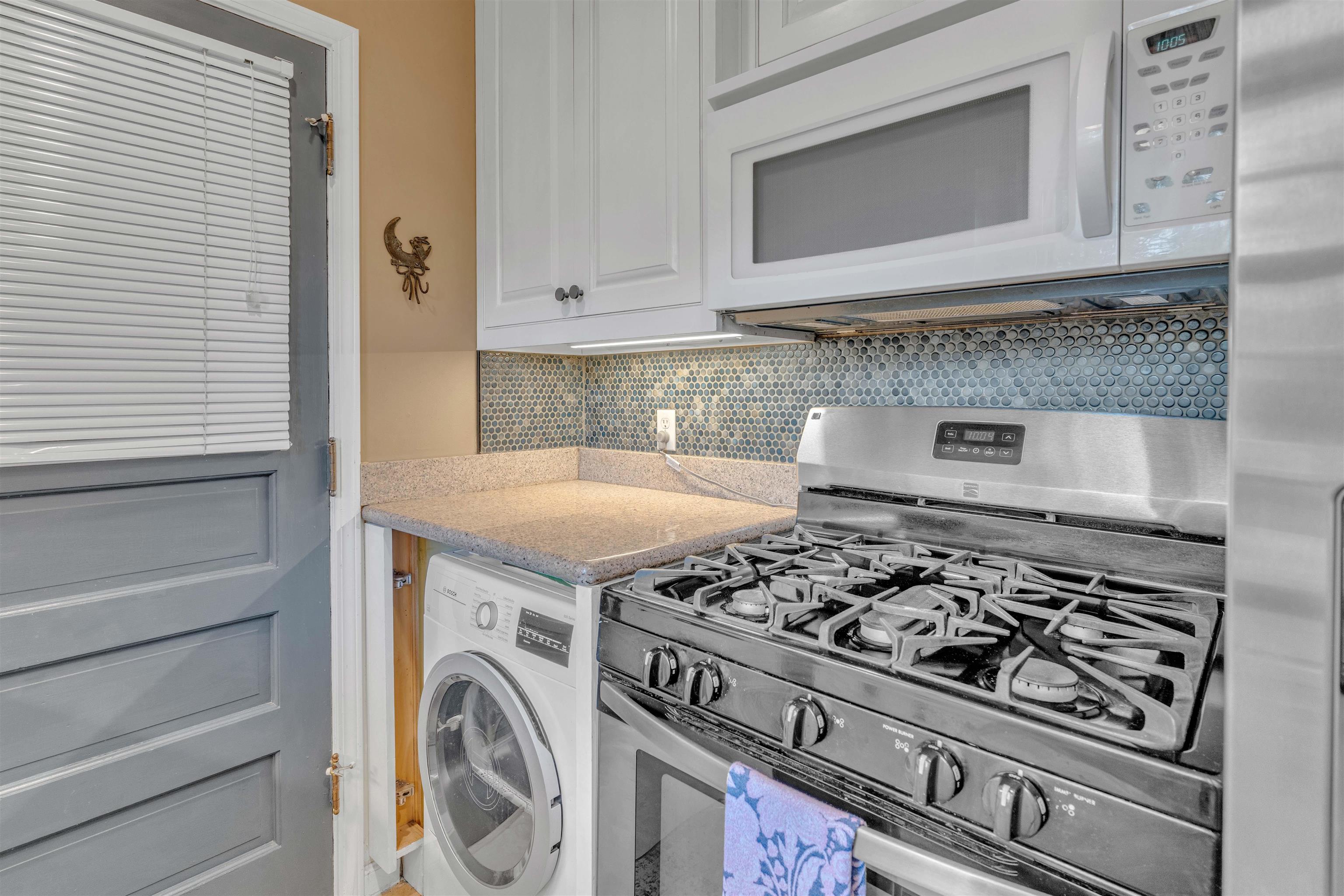 4564 Verne Road Memphis, TN 38117 - Photo 9 of 25 Compact kitchen featuring a stainless steel gas range, over-the-range microwave, white cabinetry, and a penny tile backsplash