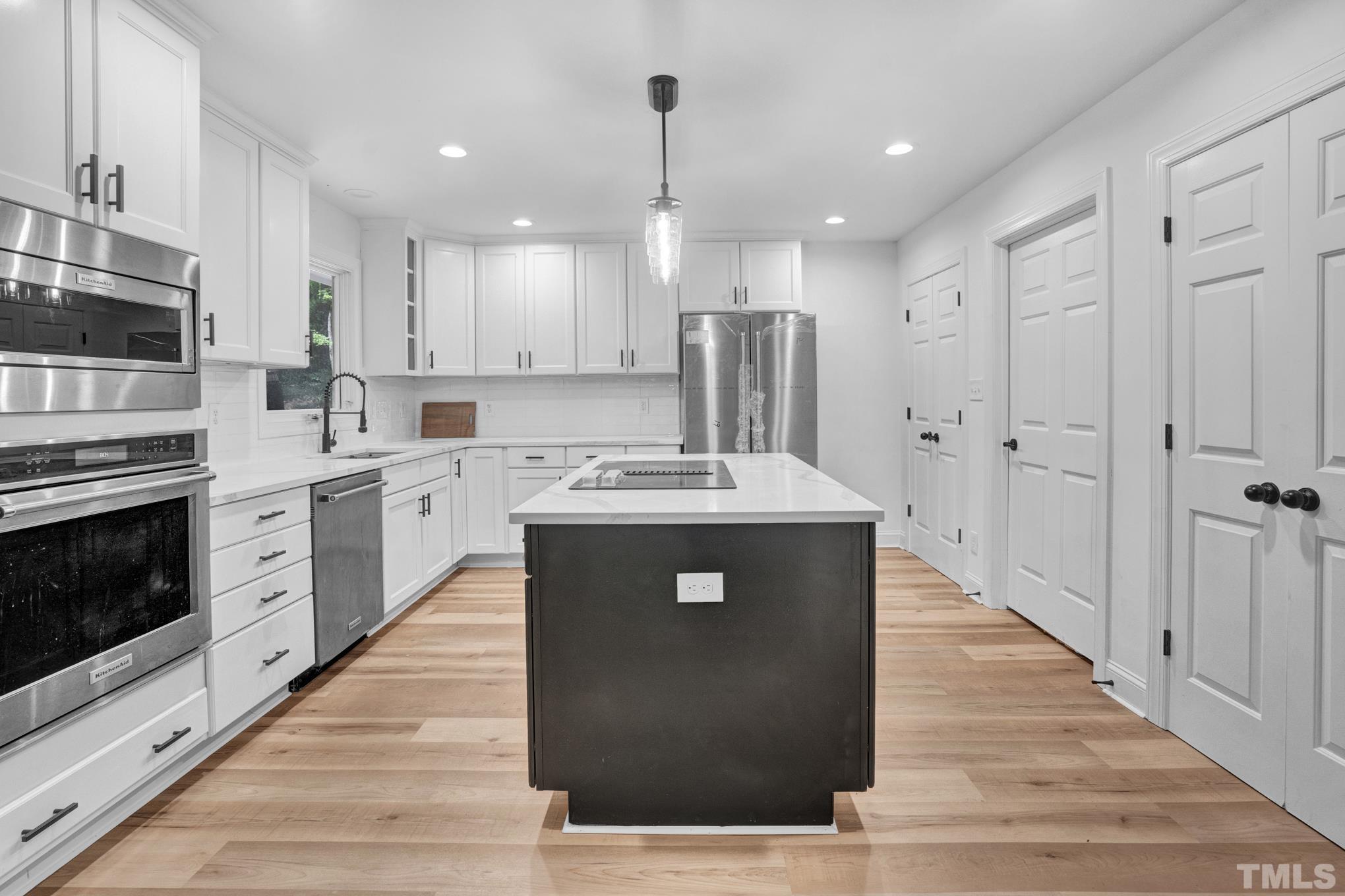 12600 Old Creedmoor Road Raleigh, NC 27613 - Photo 14 of 24 a kitchen with stainless steel appliances kitchen island granite countertop a refrigerator a sink dishwasher a stove and white cabinets with wooden floor