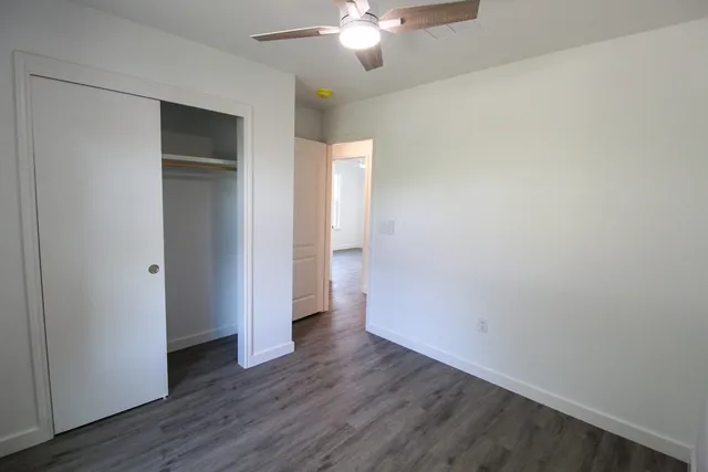 an empty room with wooden floor and a ceiling fan