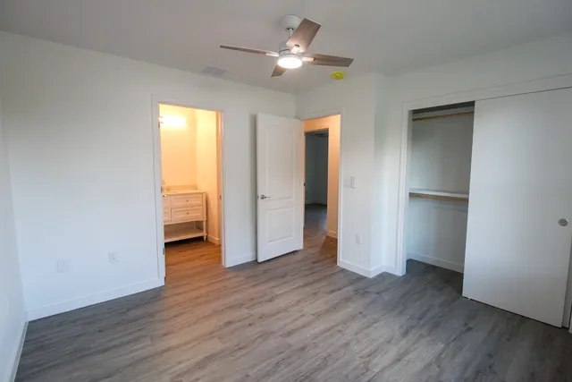 a view of empty room with wooden floor and fan