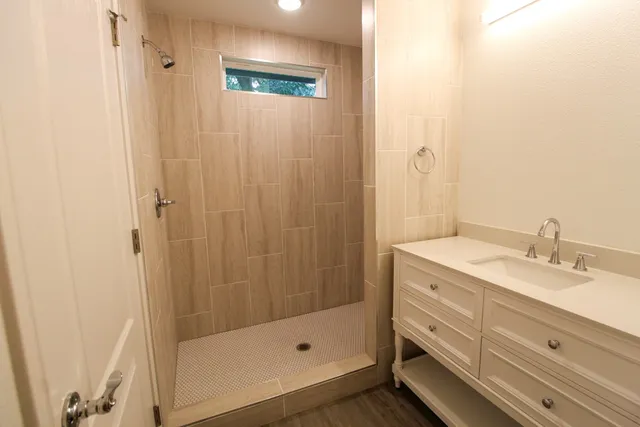 a bathroom with a granite countertop sink a mirror and a shower