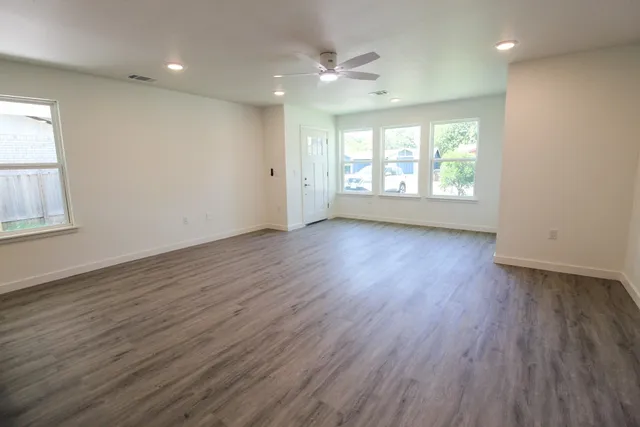 an empty room with wooden floor and windows