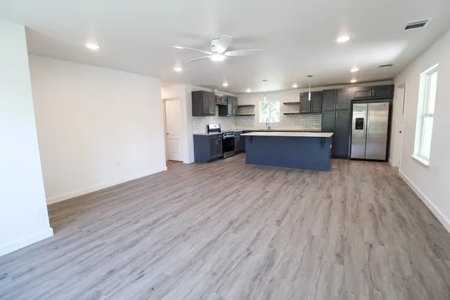 a large kitchen with stainless steel appliances kitchen island a large counter top and a wooden floors