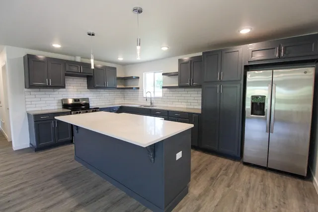 a kitchen with stainless steel appliances granite countertop a sink a refrigerator and a stove top oven