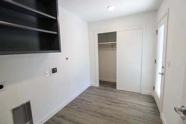 a view of an empty room with wooden floor and windows