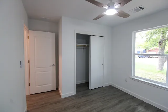 a view of an empty room with wooden floor and a window