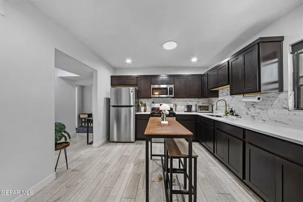 a kitchen with stainless steel appliances kitchen island granite countertop a refrigerator a sink dishwasher a stove with wooden cabinets and floor