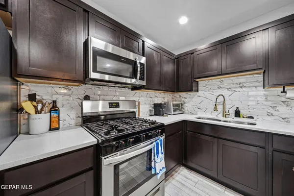 a kitchen with stainless steel appliances granite countertop a sink stove and microwave