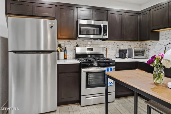 a kitchen with granite countertop a refrigerator stove microwave and sink