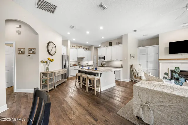 a living room with furniture kitchen view and a chandelier