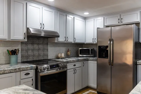 a kitchen with stainless steel appliances granite countertop a sink stove refrigerator and cabinets
