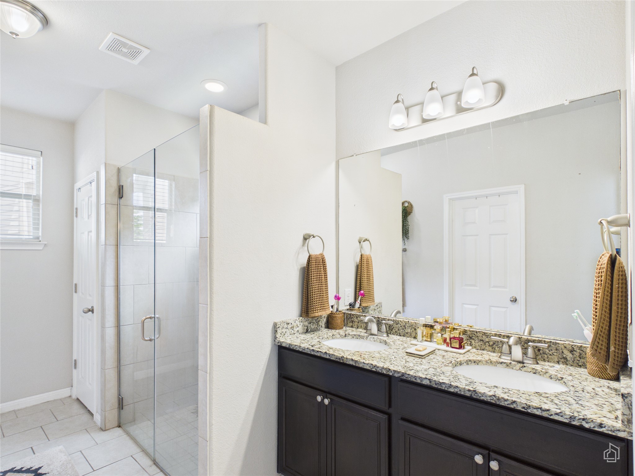 9310 Tanager Way Austin, TX 78748 - Photo 11 of 32 Double vanity with granite counters and a glass-enclosed shower elevate this private bath.