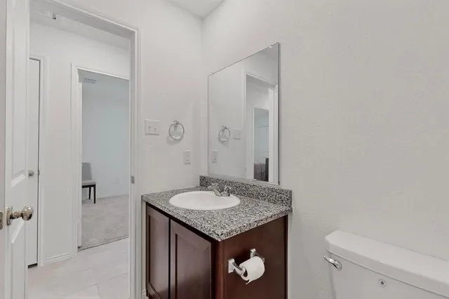 a bathroom with a granite countertop sink a toilet and mirror