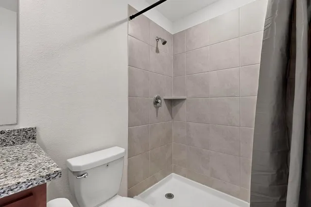 a bathroom with a granite countertop sink and a toilet