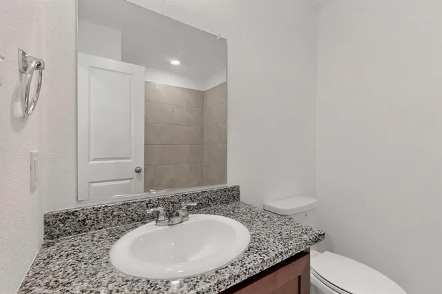 a bathroom with a granite countertop sink a mirror and a toilet
