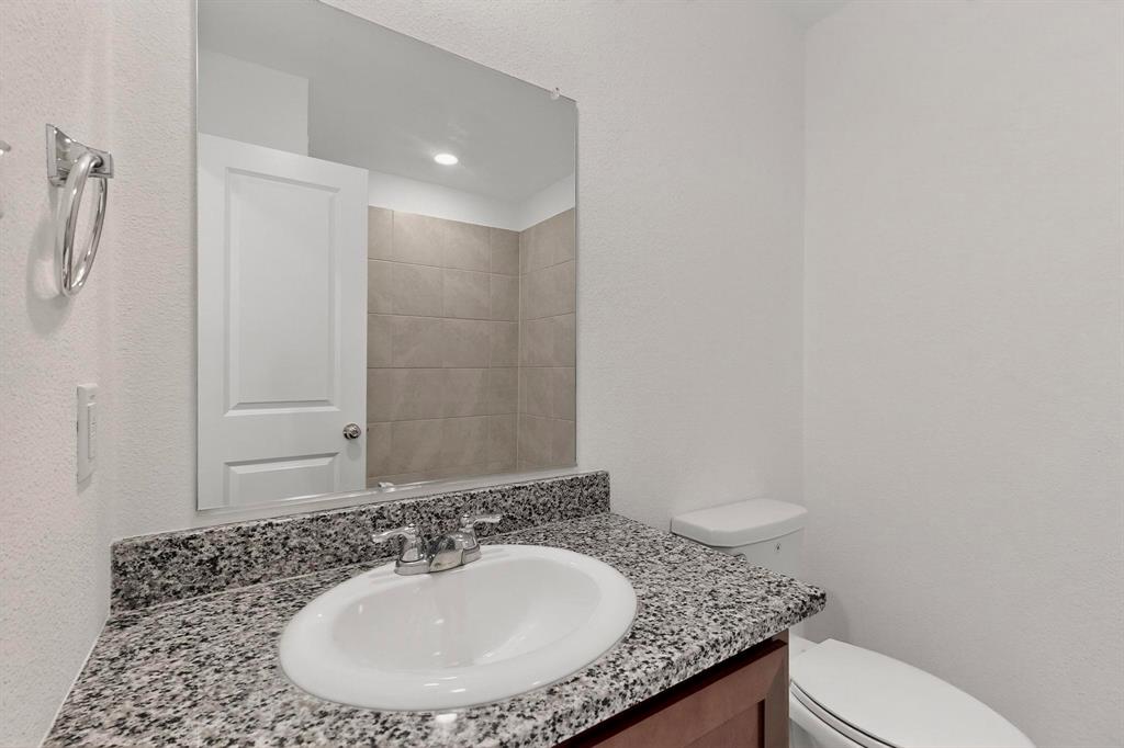 154 Herman Lane Princeton, TX 75407 - Photo 27 of 37 a bathroom with a granite countertop sink a mirror and a toilet