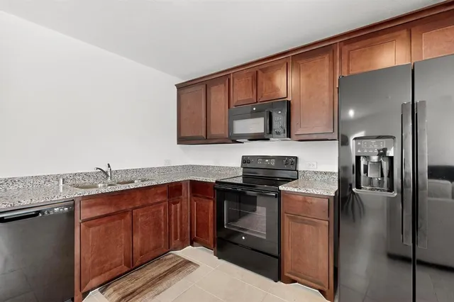 a kitchen with stainless steel appliances granite countertop a refrigerator a stove a sink and a microwave