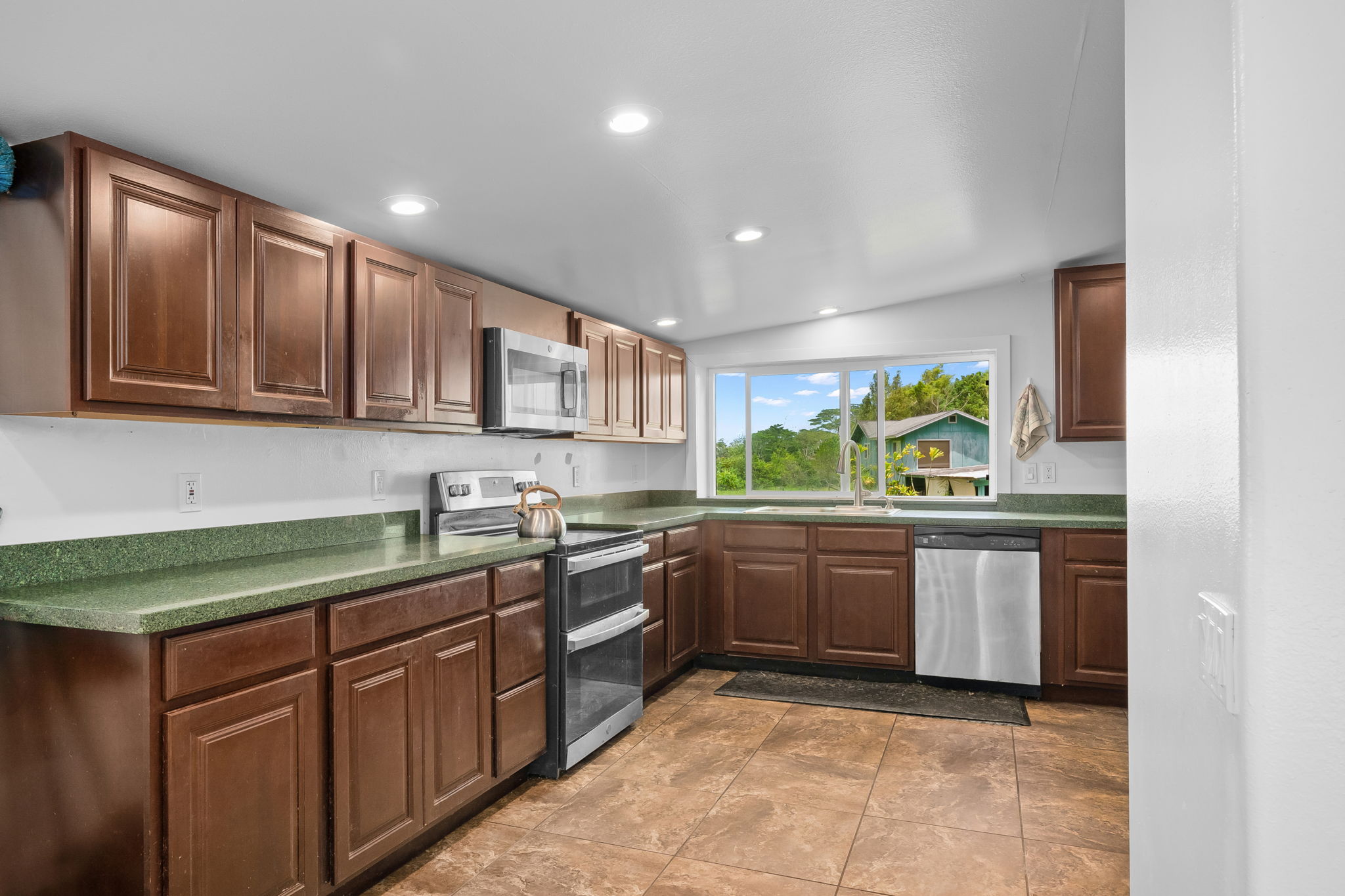 7060 Kahuna Road Kapaa, HI 96746 - Photo 9 of 30 a kitchen with kitchen island granite countertop stainless steel appliances stove sink and cabinets