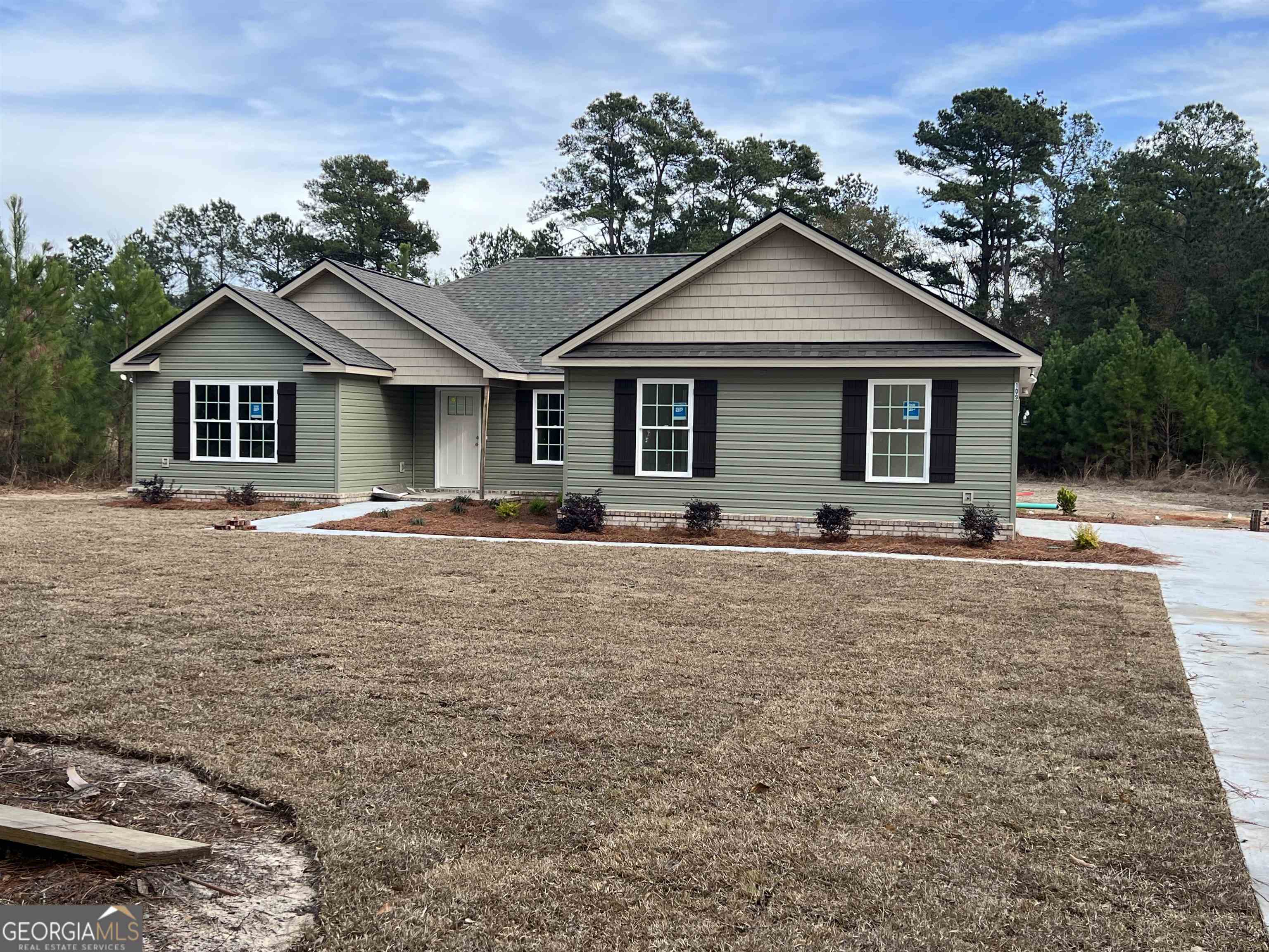 a front view of house with yard and trees in the background