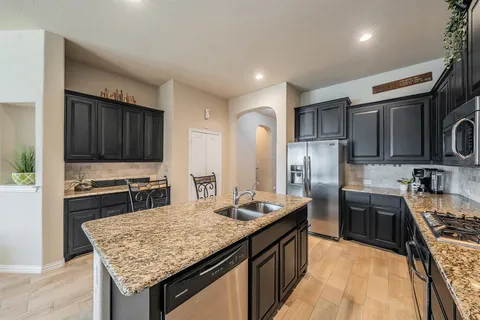 a kitchen with stainless steel appliances granite countertop a stove refrigerator and a sink