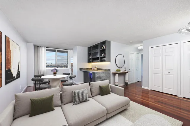 a living room with furniture a large window and wooden floor