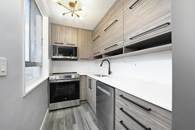 a kitchen with stainless steel appliances a sink dishwasher a stove top oven a refrigerator with island and cabinets