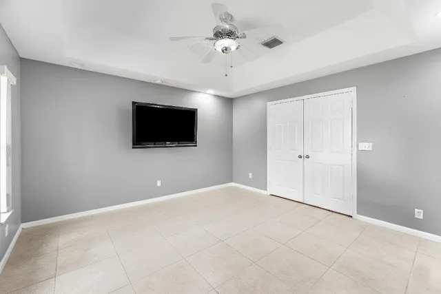 an empty room with a chandelier fan and windows