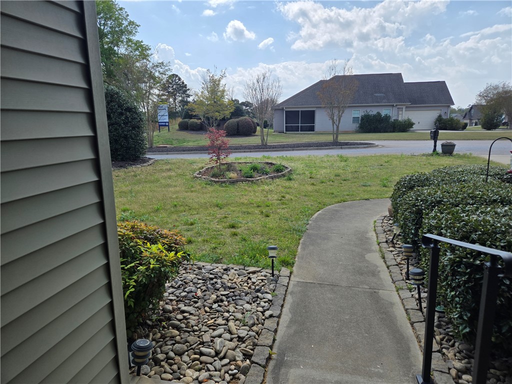 304 Knoll View Drive Seneca, SC 29678 - Photo 29 of 36 A concrete path leads to a well-maintained lawn with lush greenery and mature trees.