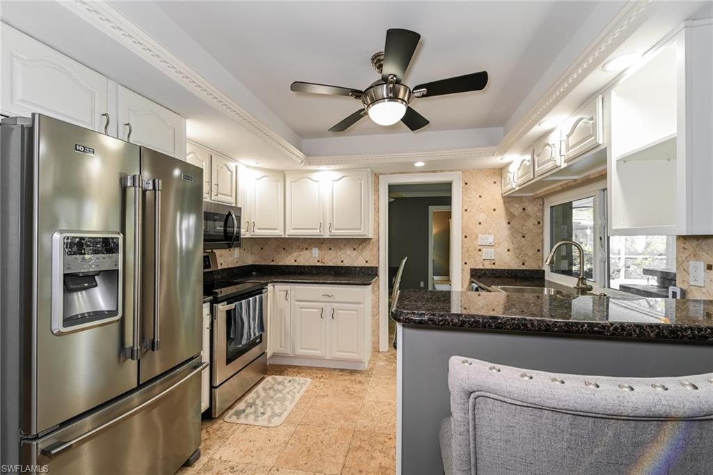 283 Forest Hills Boulevard Naples, FL 34113 - Photo 3 of 11 Kitchen with appliances with stainless steel finishes, ceiling fan, a peninsula, white cabinetry, and a raised ceiling