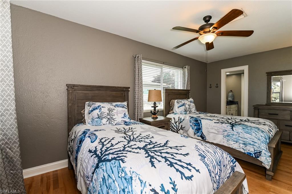283 Forest Hills Boulevard Naples, FL 34113 - Photo 10 of 11 Bedroom featuring wood finished floors, ceiling fan, a textured wall, and connected bathroom