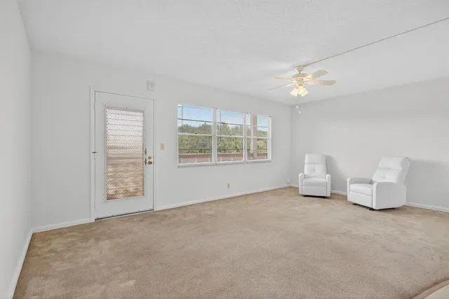 an empty room with windows and chandelier fan