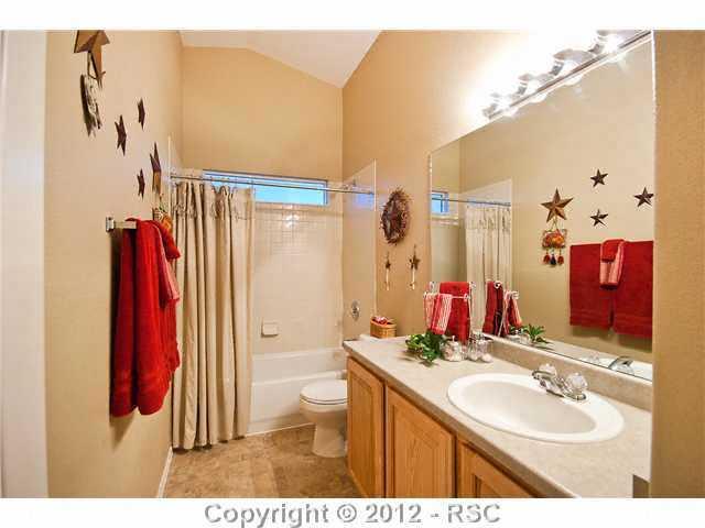 8739 Del Rio Road Peyton, CO 80831 - Photo 17 of 25 The full Hall Bath has a hickory vanity w/single sink, mirror, decorative lighting & a tub/shower w/tile surround & view window