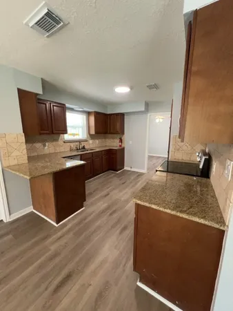 a kitchen with stainless steel appliances granite countertop a sink a stove and a wooden floors