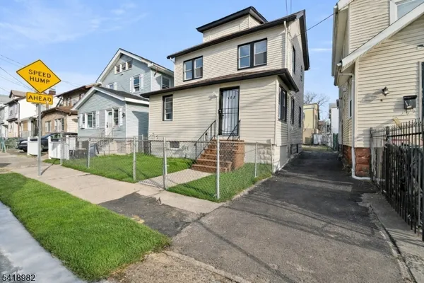 a view of a white house next to a yard with wooden fence