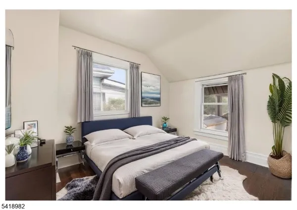 a bedroom with a bed window and potted plant on table