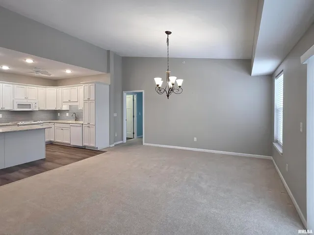 a view of a kitchen with a sink wooden cabinets and chandelier