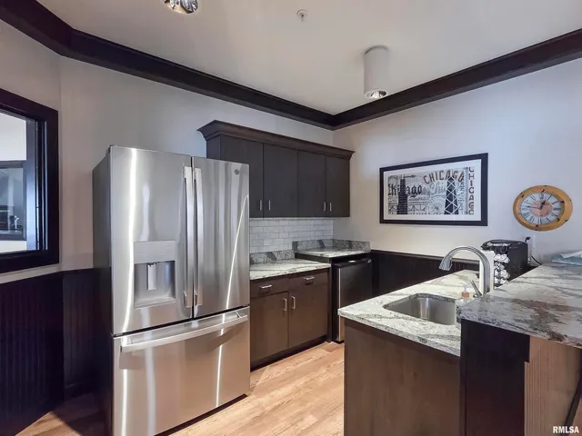 a large kitchen with stainless steel appliances a refrigerator a stove a sink dishwasher a dining table and chairs with wooden floor