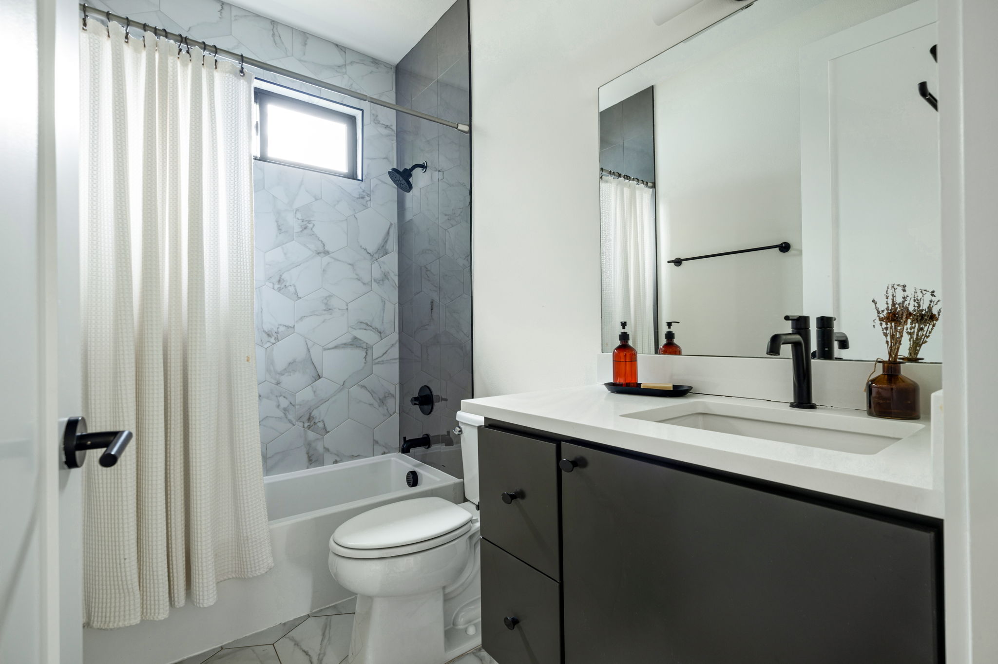 3508 Lyons Road Austin, TX 78702 - Photo 21 of 40 Modern bathroom featuring sleek black fixtures and striking hexagon-patterned tile work.