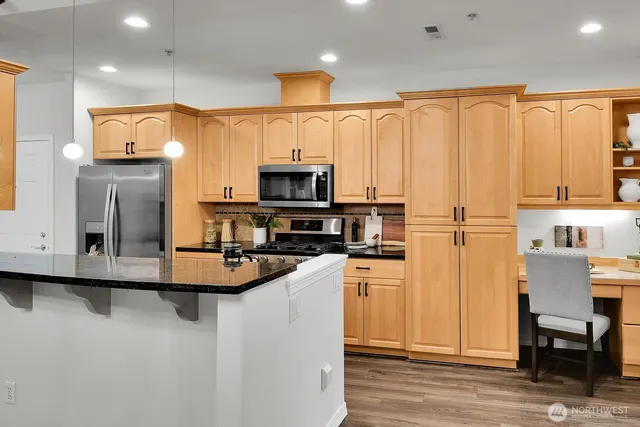 a kitchen with stainless steel appliances granite countertop a refrigerator a stove top oven a sink and dishwasher