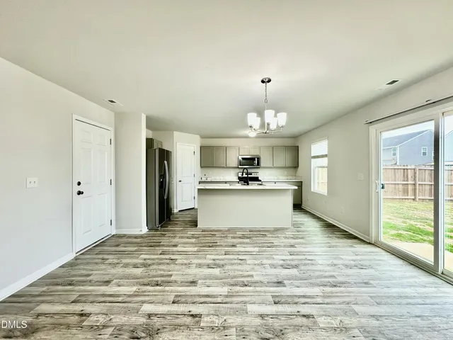 a view of a kitchen with kitchen island stainless steel appliances wooden floor and chandelier