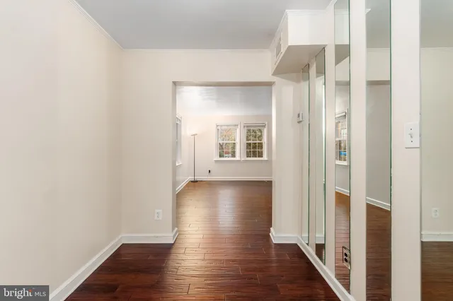 a view of a hallway with wooden floor and a bathroom