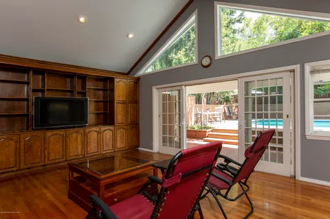 a living room with furniture a flat screen tv and a floor to ceiling window