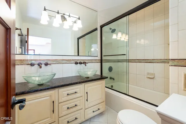 a bathroom with a granite countertop sink a mirror a bathtub and shower